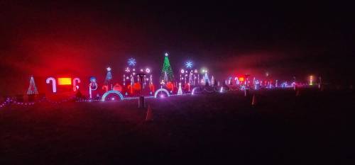A festive display of colorful Christmas lights, including trees, candy canes, and snowflakes, glowing in the night.