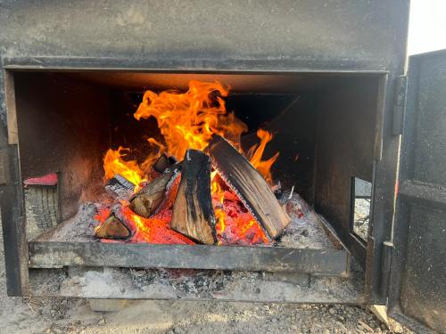 A roaring fire with bright flames and burning logs inside a metal fireplace.