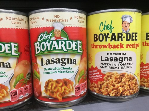 Cans of Chef Boyardee Lasagna and throwback recipe, featuring pasta in tomato and meat sauce on store shelf.