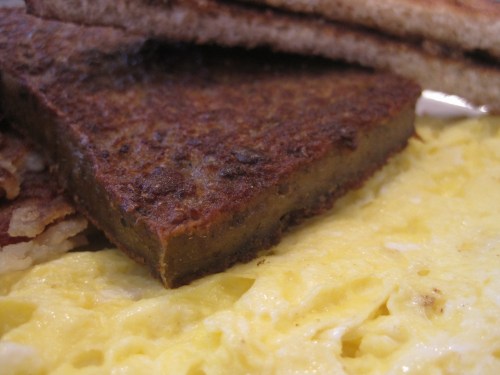 A close-up of a plate featuring a golden omelet, crispy hash browns, and toasted bread.
