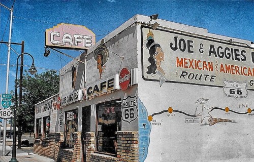 A vintage cafe building with colorful murals, featuring "Joe & Aggie's" and Route 66 signage under a clear blue sky.