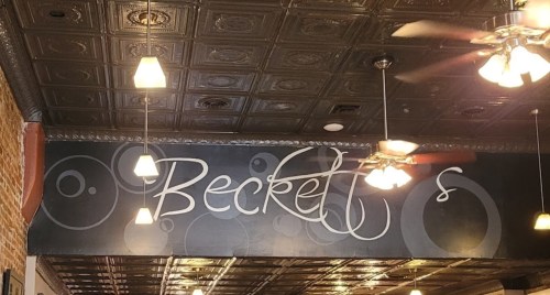 Sign for "Beckett's" in a restaurant with decorative ceiling and ceiling fans.