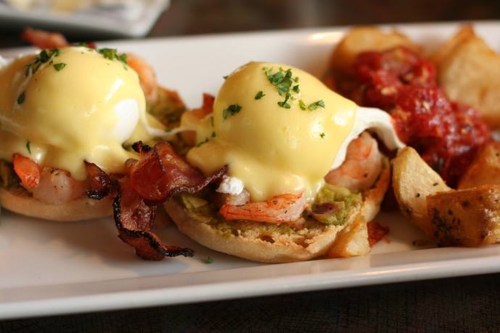 Two eggs Benedict with shrimp and bacon on English muffins, served with roasted potatoes and marinara sauce.