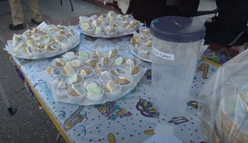 A table displays colorful dessert cups and a container labeled "Muffin Cakes" at a festive event.