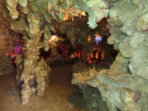 A colorful cave interior with unique rock formations and illuminated areas, creating a mystical atmosphere.