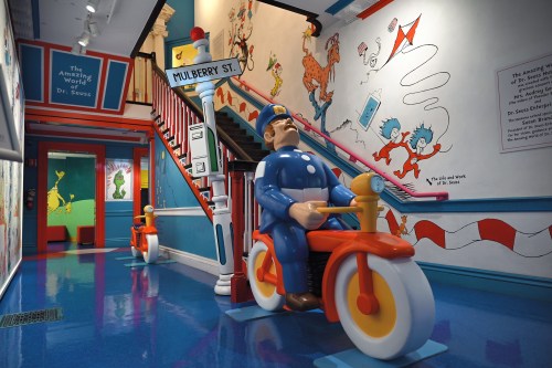 Colorful interior of a Dr. Seuss-themed exhibit featuring murals, a police officer statue, and playful decor.