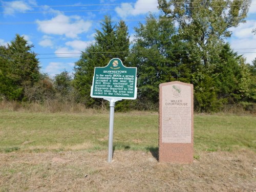 Historical markers for Shawneetown and Miller Courthouse in a grassy area with trees and a blue sky.