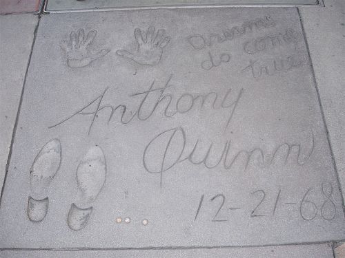 Concrete slab featuring handprints, shoe prints, and the name "Anthony Quinn" with the date "12-21-68" inscribed.
