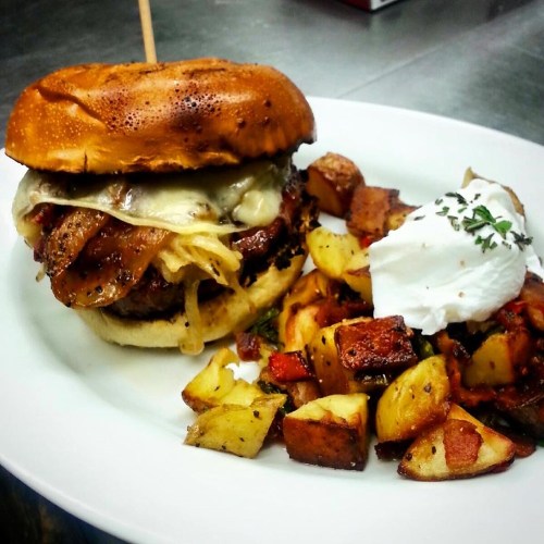 A juicy burger with melted cheese and bacon, served with seasoned roasted potatoes and a dollop of sour cream.