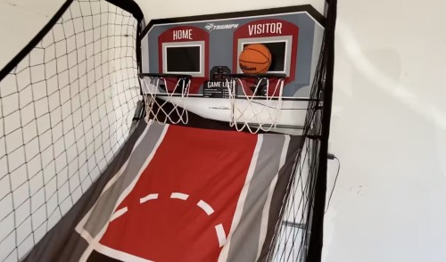 A basketball arcade game with two hoops, score displays, and a basketball on a sloped playing surface.