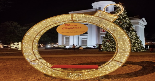 A festive Christmas display in Canton, Mississippi, featuring a large illuminated ornament and a decorated tree.