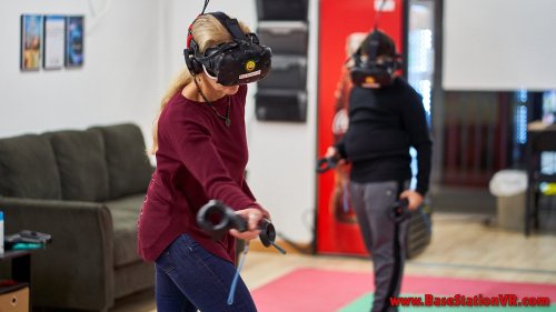 Two people wearing VR headsets engage in virtual reality gameplay in a modern gaming space.