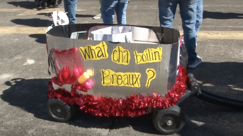 A decorated wagon with a sign reading "What cha boilin' Breaux?" surrounded by festive red tinsel.