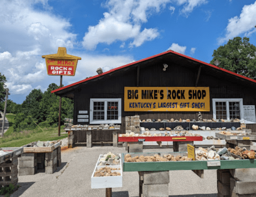 Exterior of Big Mike's Rock Shop with colorful signs, showcasing various rocks and gifts under a blue sky.