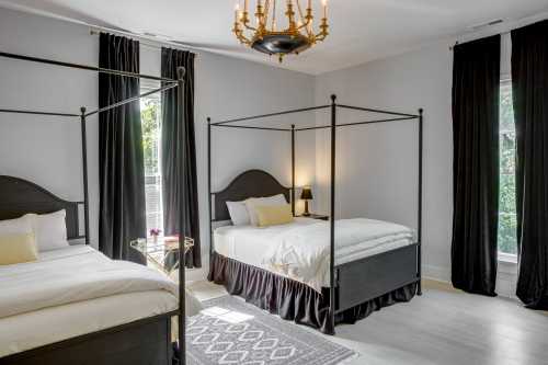 Two elegant bedrooms with black four-poster beds, white bedding, and large windows dressed in black curtains.