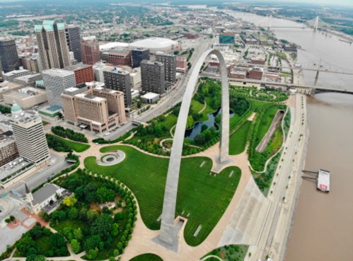 Aerial view of the Gateway Arch in St. Louis, surrounded by green parks and the Mississippi River.