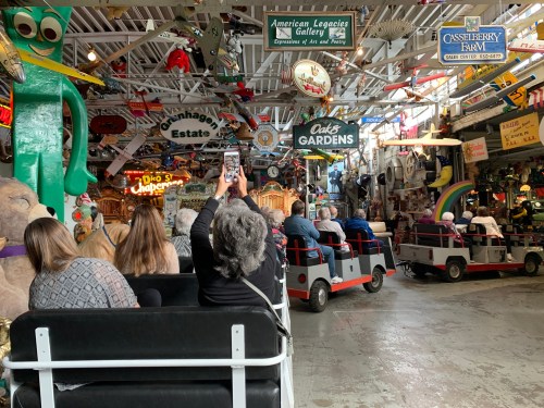 A group of people on a ride in a quirky indoor amusement space filled with colorful decorations and memorabilia.
