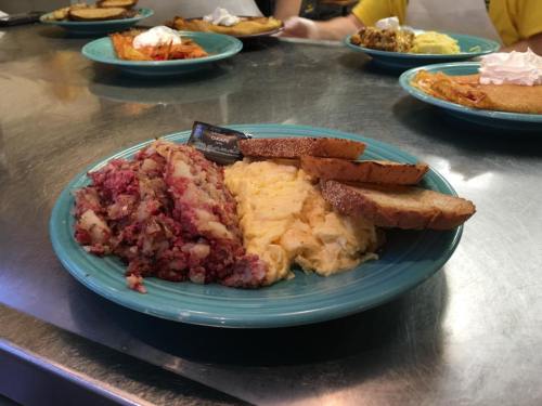 A plate with hash browns, scrambled eggs, two slices of toast, and a packet of butter on a blue dish.