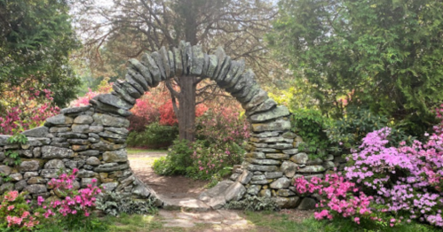 A stone archway surrounded by vibrant flowers and lush greenery in a serene garden setting.