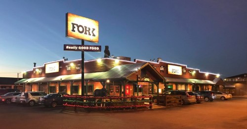 A cozy restaurant named "Fork" with bright signage and festive lights, set against a twilight sky.