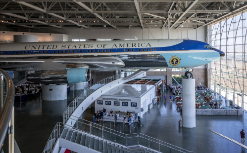 A historic airplane, labeled "United States of America," displayed in a spacious museum with visitors below.
