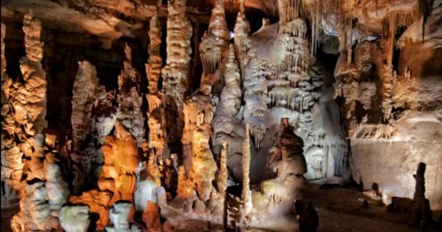 A stunning cave interior featuring colorful stalagmites and stalactites illuminated by soft lighting.