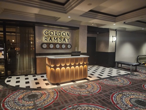 Entrance of Gordon Ramsay Steak, featuring a stylish reception desk and patterned flooring.
