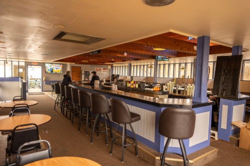 A spacious bar area with high stools, tables, and a counter, featuring a warm, inviting atmosphere.