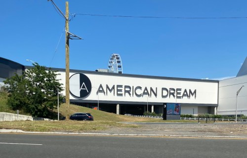 Sign for "American Dream" shopping and entertainment complex, with a Ferris wheel visible in the background.
