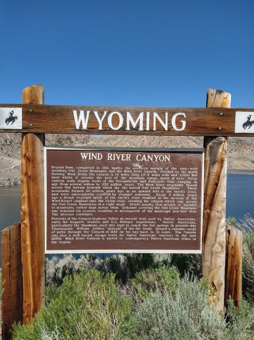 Sign marking Wind River Canyon in Wyoming, with historical information and scenic background of the canyon and river.