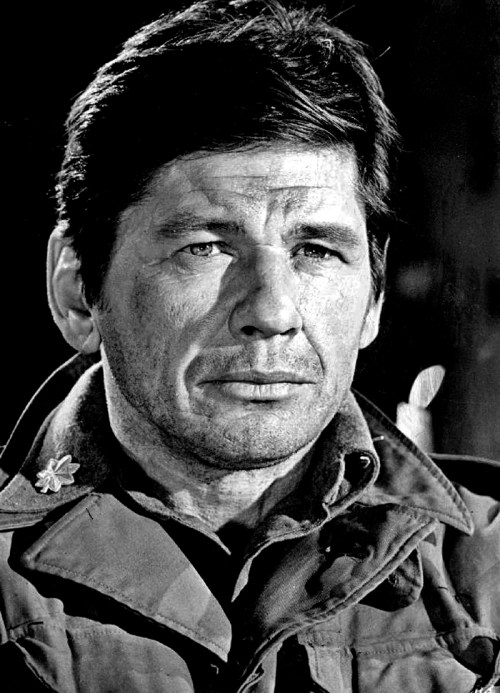 A close-up of a serious man in military attire, with short dark hair and a contemplative expression.