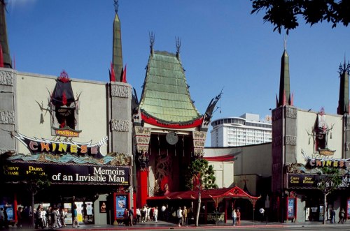 Exterior of Grauman's Chinese Theatre, featuring movie posters and distinctive architecture under a clear blue sky.