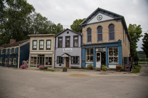 A quaint street scene featuring colorful buildings, including a shop named "Anne's," with flowers in planters.