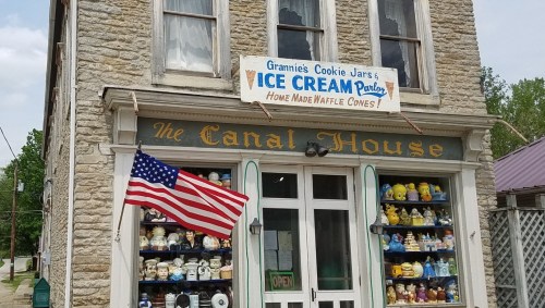 A stone building with a sign for "Grammie's Cookie Jars & Ice Cream Parlor" and an American flag out front.
