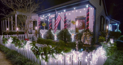 A beautifully decorated house for the holidays, featuring lights, wreaths, and an American flag.