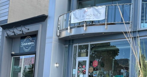 Exterior view of a building featuring "Cloud Ninth" and "Salt & Honey" signs, with a balcony above.