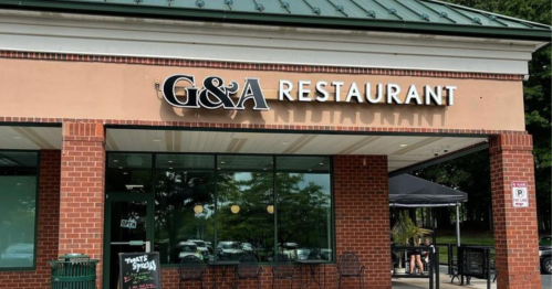 Exterior view of G&A Restaurant, featuring a brick facade and large windows, with outdoor seating visible.