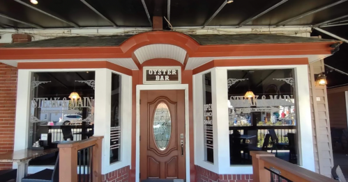 Exterior view of a restaurant with a sign reading "Oyster Bar," featuring a wooden door and large windows.