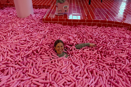 A woman is immersed in a pool of pink sprinkles at the Museum of Ice Cream in Boston, Massachusetts.