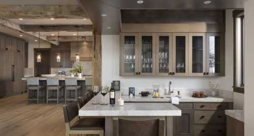 Modern kitchen with a marble island, wooden cabinets, and a dining area in the background, featuring stylish lighting.