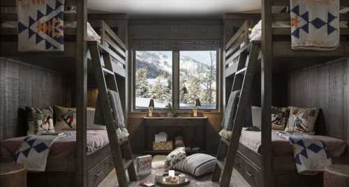 Cozy cabin-style room with two sets of bunk beds, warm decor, and a snowy landscape visible through the window.