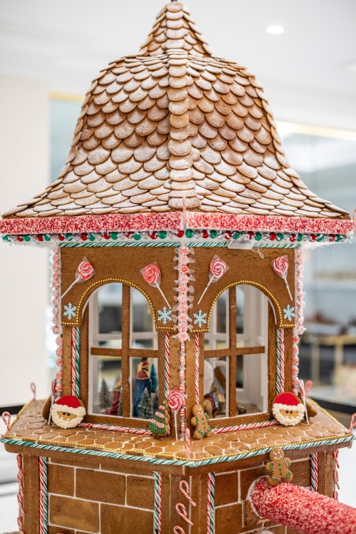 A beautifully decorated gingerbread house with a shingled roof, candy accents, and festive details.