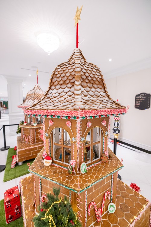 Two intricately decorated gingerbread houses with candy accents and festive details, set in a bright, elegant space.