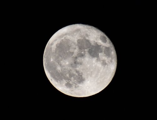 A bright full moon against a dark night sky, showcasing its craters and surface details.
