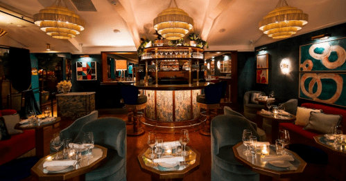 Elegant restaurant interior featuring a stylish bar, plush seating, and ambient lighting.