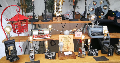 A display of vintage items including cameras, typewriters, and a saxophone, with decorative light bulbs and a sign.