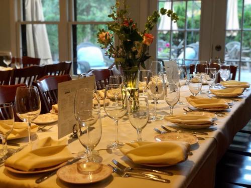 A beautifully set dining table with yellow napkins, glassware, and a floral centerpiece, ready for a meal.