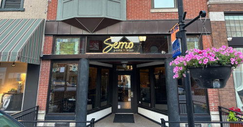 Exterior view of Semo restaurant, featuring a welcoming entrance and flower baskets, set in a brick building.