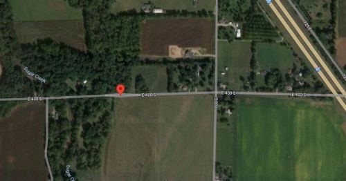 Aerial view of a rural area with roads, fields, and patches of trees, featuring a marked location.