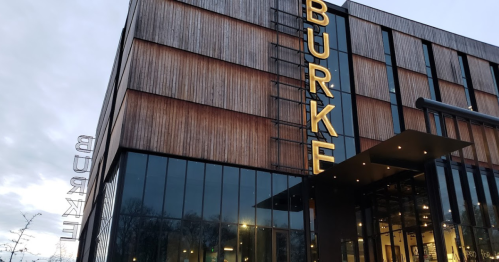 Modern building with wooden facade and large glass windows, featuring the name "BURKE" in bold yellow letters.